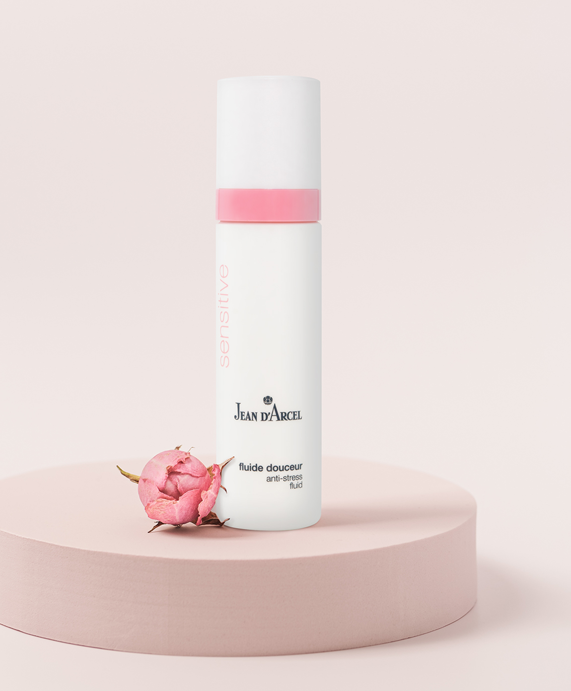 Pflegeprodukt auf einem rosafarbenem Podest mit dekorativen Blüten.